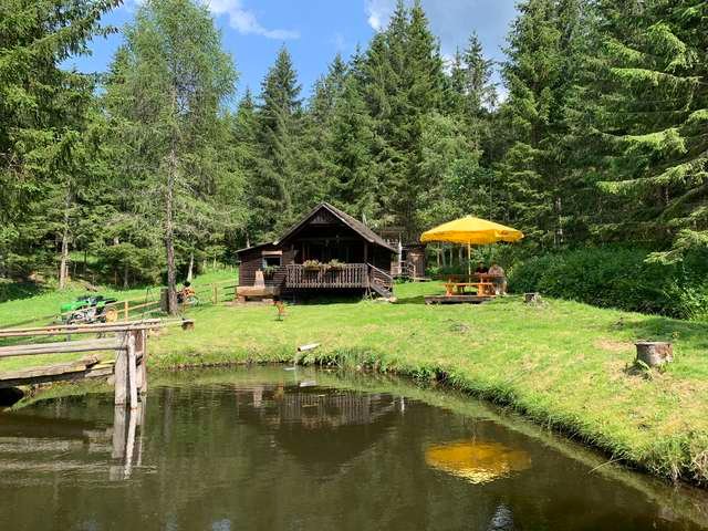 Die Fischerhütte am eigenen Teich, umgeben von Wald