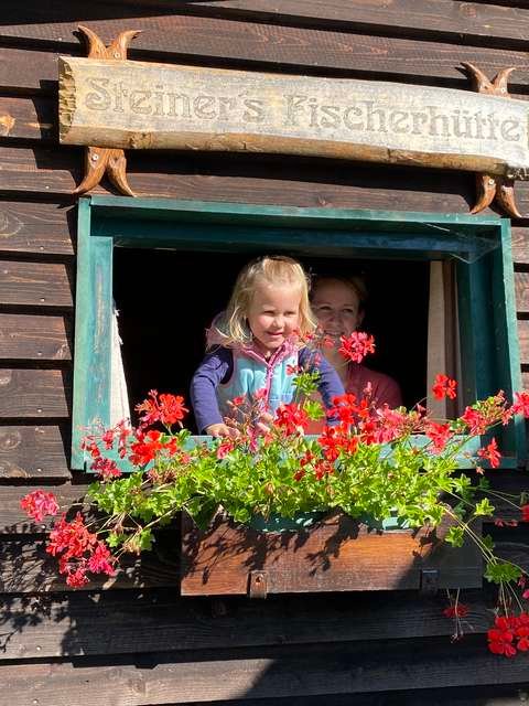 Ein Kind schaut aus dem Fenster der Fischerhütte